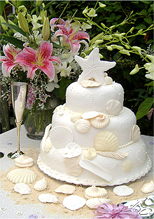 three layer rounded wedding cake with shells, sand detail, and a starfish topper