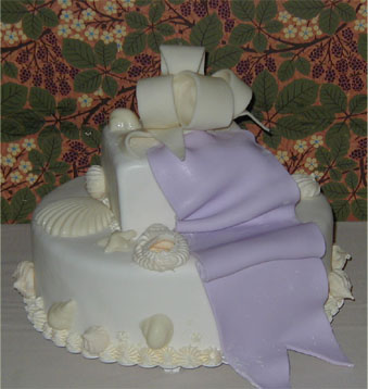 two layer scallop and shell cake with purple ribbon