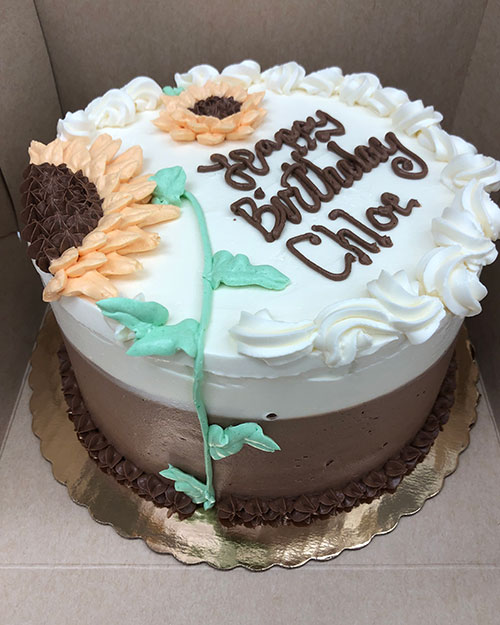 A cake with sunflower icing that reads Happy Birthday Chloe