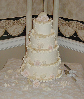 four layer ivory cake with shells and pink roses