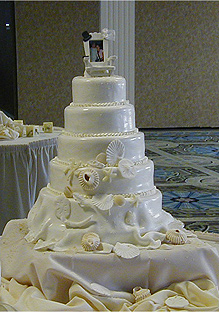 five layer glossy white wedding cake with seashells