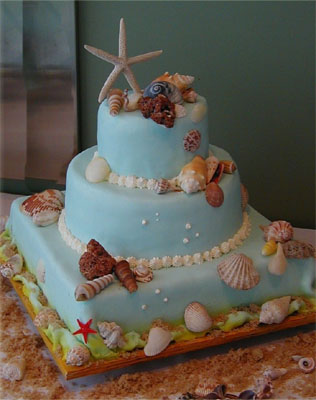 ocean blue three layer wedding cake with realistically painted seashells and a starfish