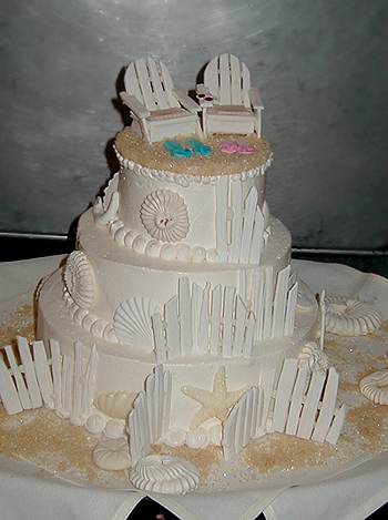 three layer wedding cake with adirondack chairs and seashells