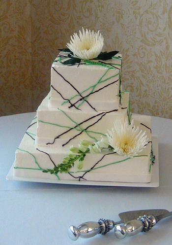 three layer square cake with green and brown drizzle and flowers