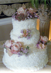 three tier cake with white fluffy frosting and pink roses