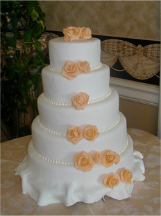 five layer cake with draped fondant and peach roses