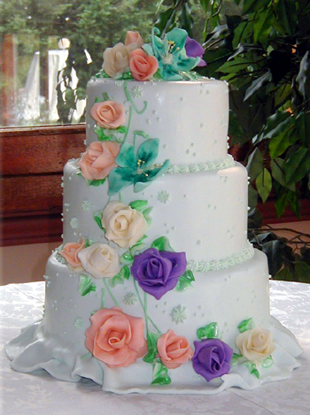 three layer cake with peach and purple roses