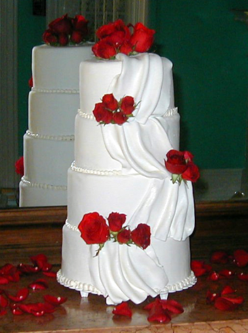 four layer white cake with draping and red roses