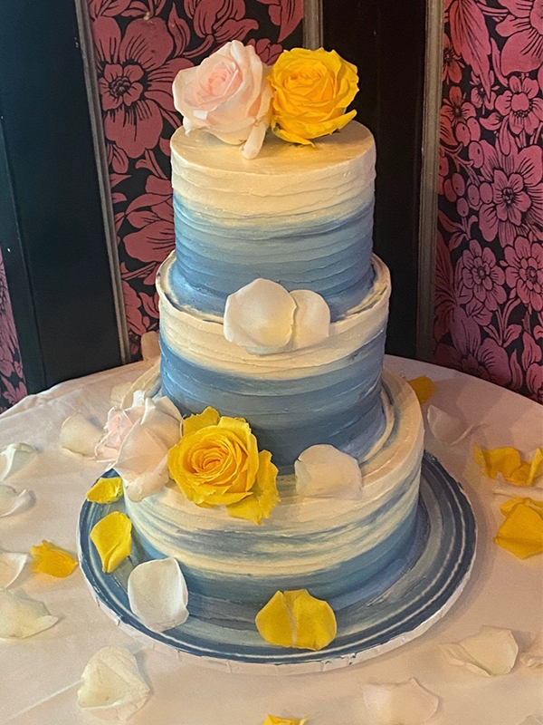 three story blue and white cake swirled like the ocean with pink and yellow roses