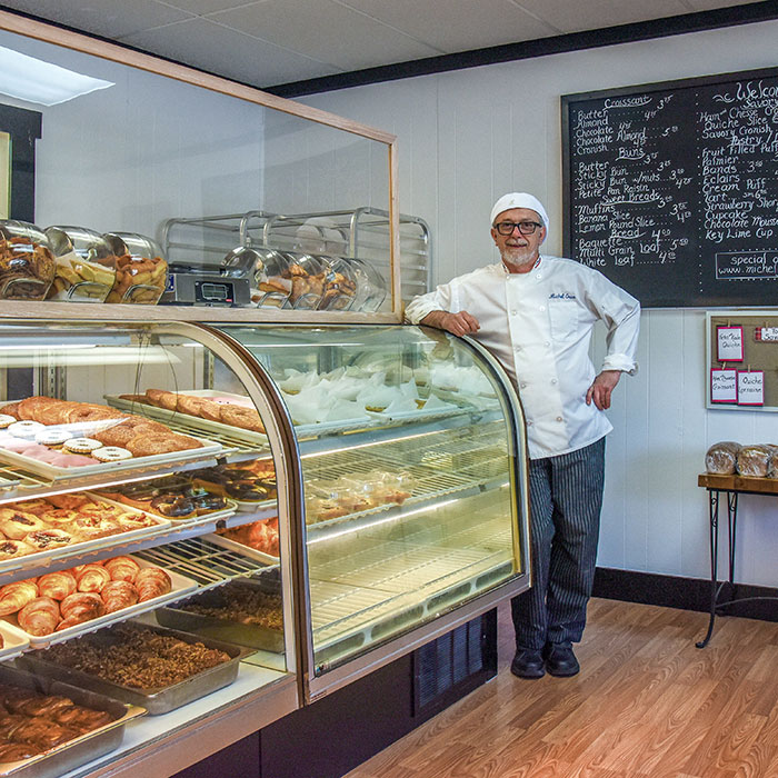 Michel Gras in front of his pastry case